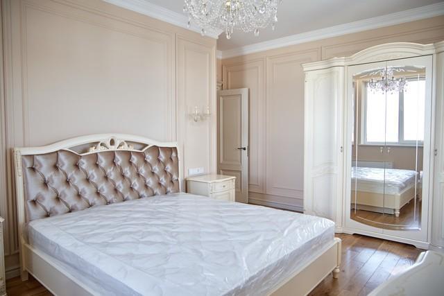 Классический стиль спальни с роскошной бежевой мебелью.